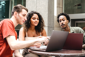Three people looking at laptop computers