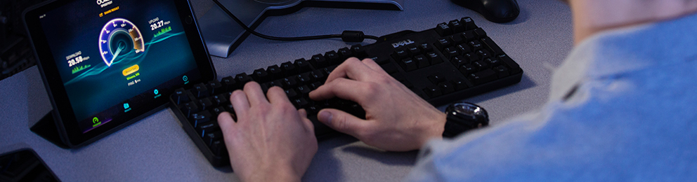 Worker's hands on a keyboard with a monitor next to it