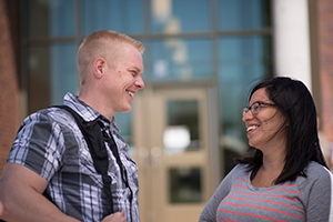 Two students on campus smiling at each other