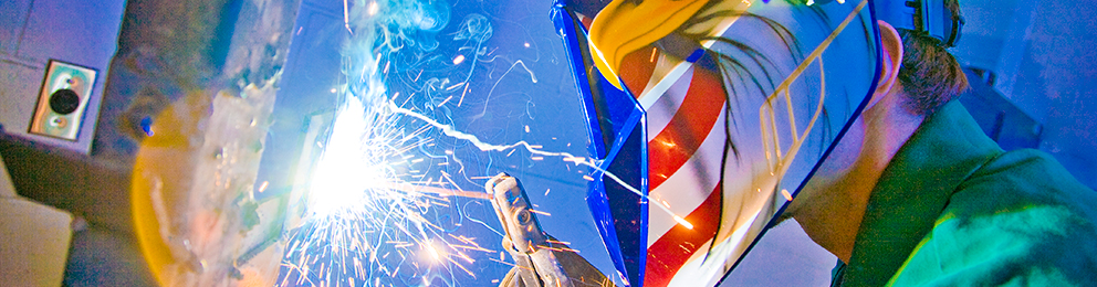 Close up of working welder with an American eagle and flag painted on his welding helmet