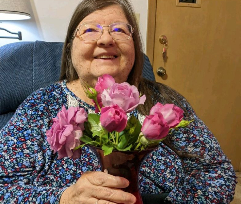 Picture of Kathy Lyman holding flowers in a vase