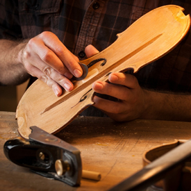 Hands using tools on a violin top