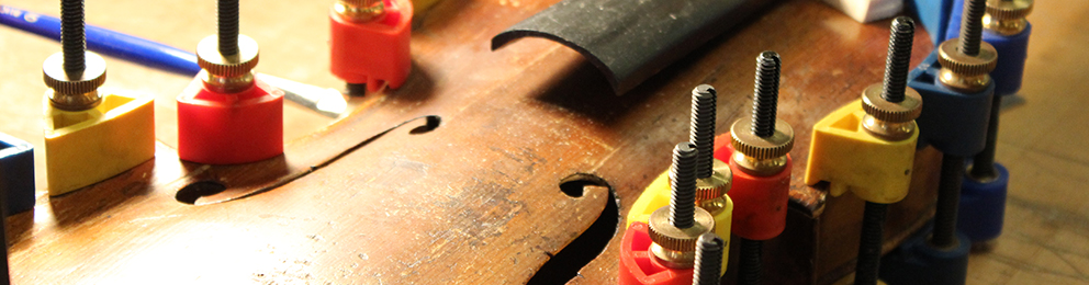 Close up of small vices attached to a violin being repaired