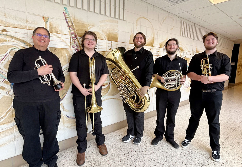 Five performers, all wearing black, holding their musical instruments