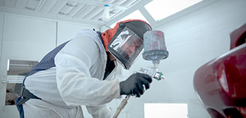 Student painting vehicle in painting bay