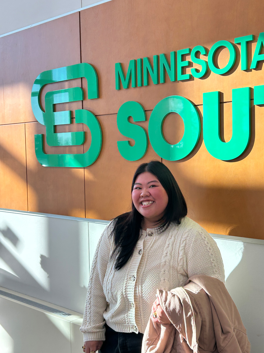 Alyvia Xiong poses for a picture in front of the Southeast logo on the Red Wing campus.