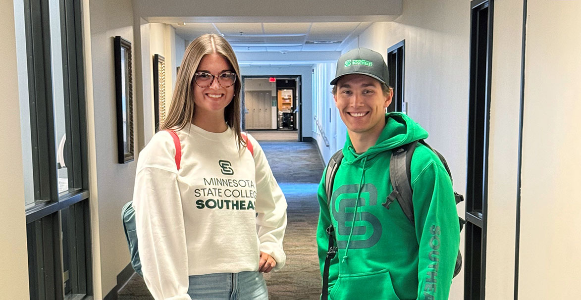 Two students wearing Southeast sweatshirts in a hallway