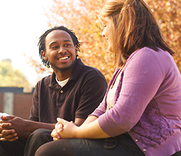Two college students sitting, talking, and smiling