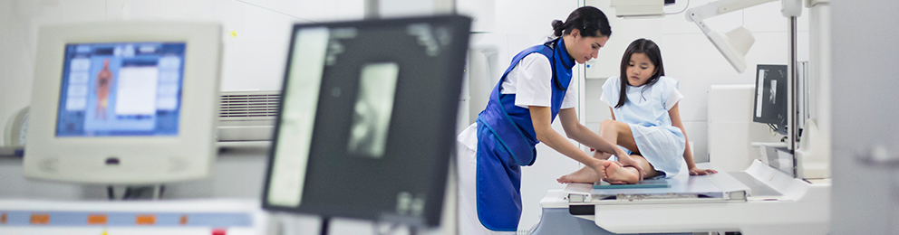 Rad tech working with a child to get an ankle x-ray