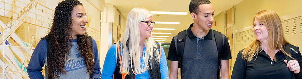 Four students walking down a college hallway