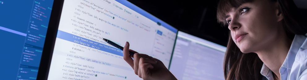 Woman pointing at code on a computer screen with a pen